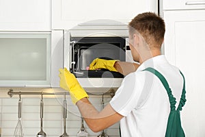 Male janitor cleaning microwave oven