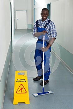 Male Janitor Mopping In Corridor