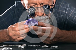 Male jeweler evaluating amethyst in workshop