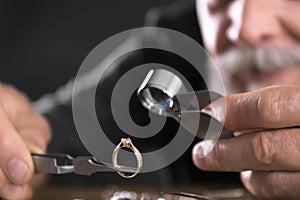 Male jeweler evaluating diamond ring in workshop