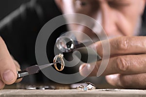 Male jeweler evaluating diamond ring in workshop