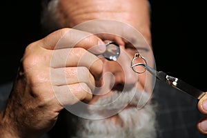 Male jeweler evaluating diamond ring in workshop