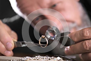 Male jeweler evaluating diamond ring in workshop, closeup