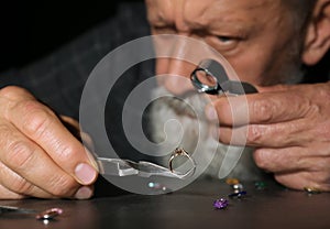 Male jeweler evaluating diamond ring in workshop, closeup