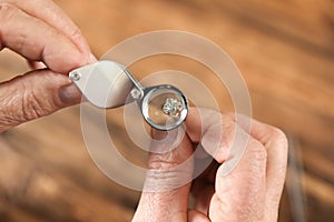 Male jeweler evaluating earring at table in workshop