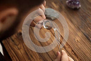 Male jeweler evaluating precious gemstone at table