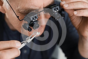 Male jeweler evaluating precious gemstone in workshop