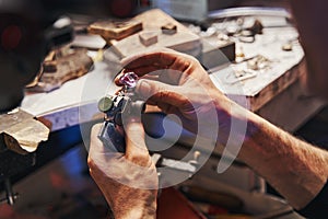 Male jeweler turning amethyst on gem-cutting tool