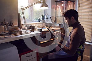 Male Jeweller Looking At Ring Design On Digital Tablet In Studio