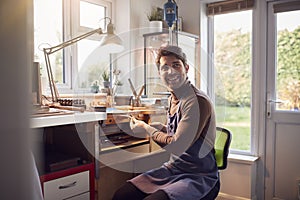 Male Jeweller Wearing Apron At Bench Working In Studio photo