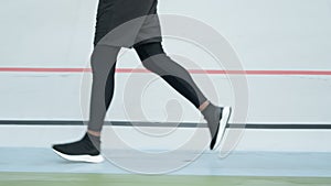 Male jogger training at stadium track. Athlete legs running on racetrack