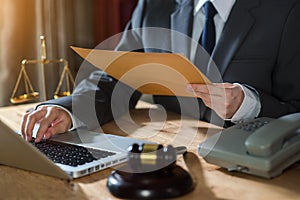 Male judge in a courtroom with the gavel working with digital tablet computer docking keyboard on wood table.