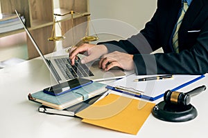 A male judge in the courtroom on a wooden table and a counselor or lawyer working in the office. A law with golden hammers and sca