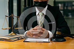 A male judge in the courtroom on a wooden table and a counselor or lawyer working in the office. A law with golden hammers and sca