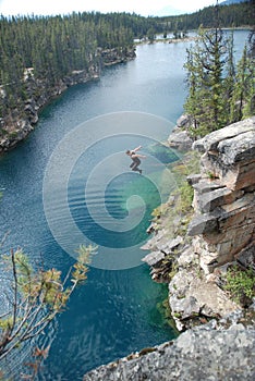 Male jumping off cliff into horseshoe lake