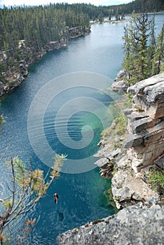 Male jumping off cliff into horseshoe lake