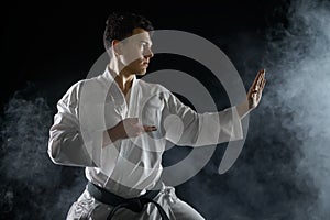 Male karate fighter in white kimono, combat stance
