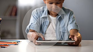 Male kid enthusiastically playing on tablet, gaming addiction, behavior problem
