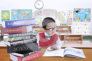 Male kid studying with lesson books in class