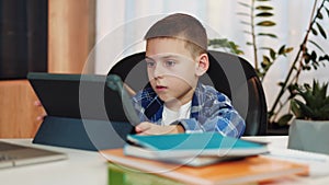 Male kid taking part in remote education using digital tablet at living room