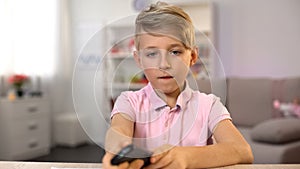 Male kid watching television instead drawing, changing channels remote control