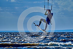 A male kiteboarder jumps above the surface of the water of a large river.