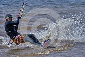 A male kiteboarder rides on a board on a large river.