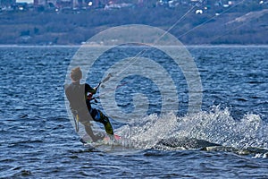 A male kiteboarder rides on a board on a large river.