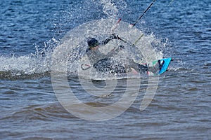 A male kiteboarder rides on a board on a large river.