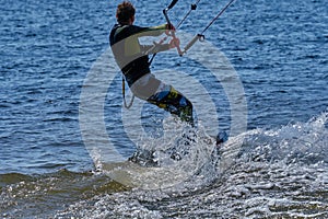 A male kiteboarder rides on a board on a large river.