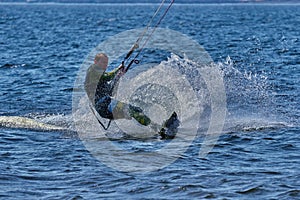 A male kiteboarder rides on a board on a large river.