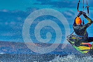 A male kiter jumps over a large lake.