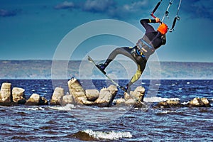 A male kiter jumps over a large lake. Close-up