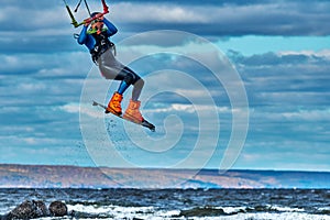 A male kiter jumps over a large lake. Close-up