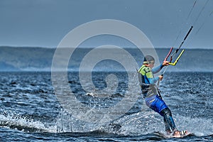 A male kiter slides on the surface of the water.