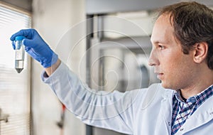 Male lab technician holding a test tube with sample