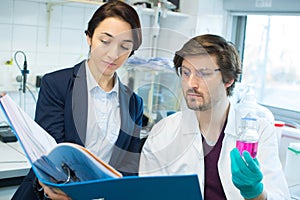Male lab worker making notes with female manager