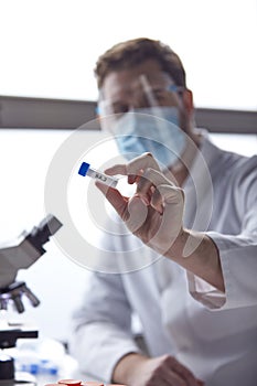 Male Lab Worker Wearing PPE Researching Covid-19 BA.2 Variant In Laboratory With Microscope