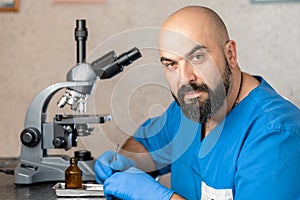 Male laboratory assistant examining biomaterial samples in a microscope