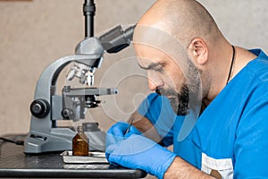 Male laboratory assistant examining biomaterial samples in a microscope