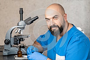 Male laboratory assistant examining biomaterial samples in a microscope