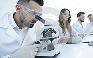 Male laboratory technician looking at samples in the microscope