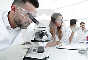 Male laboratory technician looking at samples in the microscope