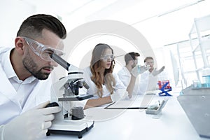 Male laboratory technician looking at samples in the microscope
