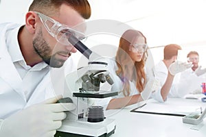 Male laboratory technician looking at samples in the microscope