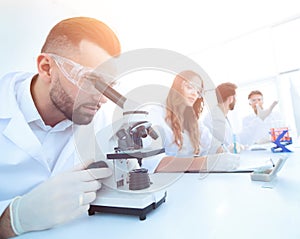 Male laboratory technician looking at samples in the microscope