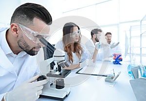 Male laboratory technician looking at samples in the microscope