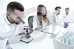 Male laboratory technician looking at samples in the microscope