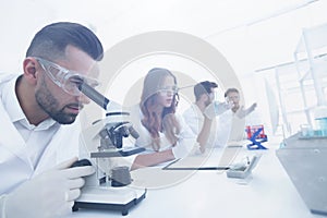 Male laboratory technician looking at samples in the microscope