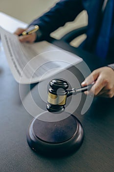 Male lawyer working with contract documents and wooden hammer on table in courtroom, justice and law,